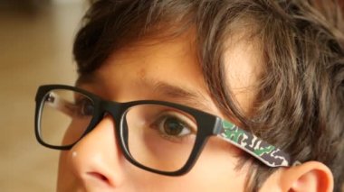 gözlüklü çocuk mesafe içine benziyor. gözleri hareket ediyor. 4 k yakın çekim. Ağır çekim. kopya alanı