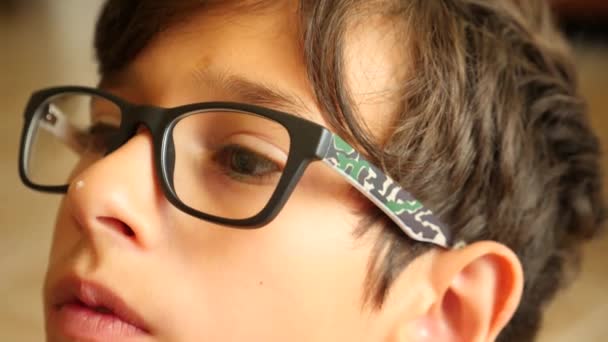 Pojken i glasögon ser i fjärran. hans ögon är rörliga. 4 k närbild. Slow motion. kopia utrymme — Stockvideo
