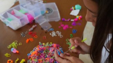 Bir kız kauçuk şeritler onun smartphone bir video ders izlerken gelen el sanatları dokuma. hobi. 4 k. ağır çekim