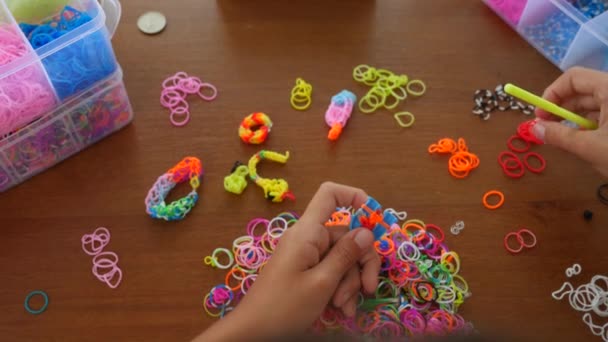 Une fille tisse des métiers de bandes de caoutchouc en regardant une leçon vidéo depuis son smartphone. hobby. 4k. Mouvement lent — Video