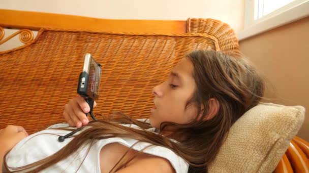A lány feküdt a kanapén, otthon, beszél a telefonon, a videó. 4k, lassú mozgás — Stock videók