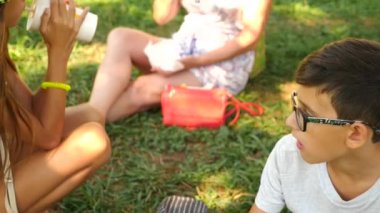 Çekici çocuk çim Park'ta bir ağacın altında oturup taze hamburger yeme. 4k, ağır çekim