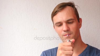 yüz genç adam bir sigara açık closeup sigara. Duman yangın ışık. oğlan içiyor. dudaklar mans. 4k, ağır çekim