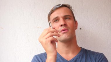 yüz genç adam bir sigara açık closeup sigara. Duman yangın ışık. oğlan içiyor. dudaklar mans. 4k, ağır çekim