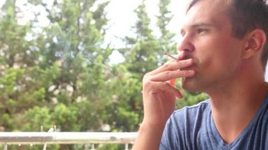 yüz genç adam bir sigara açık closeup sigara. Duman yangın ışık. oğlan içiyor. dudaklar mans. 4k, ağır çekim