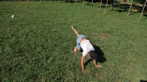 Legrační kavkazské mladík tančící na zelené trávě venku na letní slunečný den. 4k, pomalý pohyb — Stock video