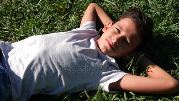 Boy 12 years old, lies on a green meadow in a summer sunny day. close-up. Slow motion. 4k — Stock Video