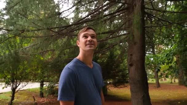 Joven hombre guapo caminando en el bosque, disfrutando de la naturaleza, 4k primer plano, disparo en cámara lenta — Vídeo de stock