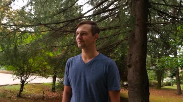 Joven hombre guapo caminando en el bosque, disfrutando de la naturaleza, 4k primer plano, disparo en cámara lenta — Vídeo de stock