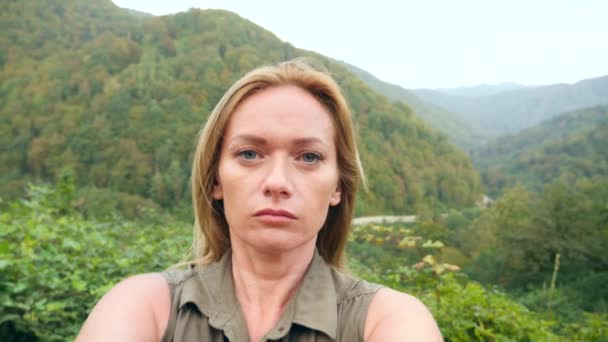 Woman having video chat using smartphone outdoors on a background of mountains, sharing travel adventure friends .Girl filming selfie video for social media. slow motion 4k — Stock Video