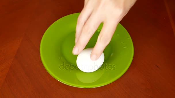 Un uomo gira un uovo di pollo per capire se è cotto o crudo. l'uovo sodo gira rapidamente. 4k. copia spazio — Video Stock
