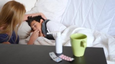 Erkek bir hasta bebek ateşi ile yatakta yatıyordu, annem hasta oğlu için bakıyor. 4k, ağır çekim silah, uzay kopyalama