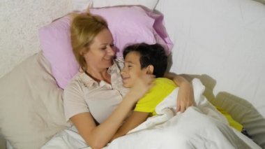 Anne ve çocukları yatakta yatan konuşuyor. 4 k. kopya alanı