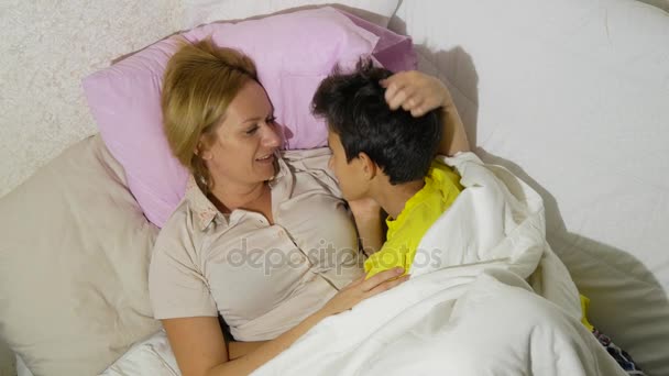 Madre y sus hijos hablando acostados en la cama. 4k. espacio de copia — Vídeo de stock