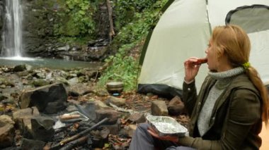 kadın ızgara sosis açık havada bir turist kampında yiyor. 4k,