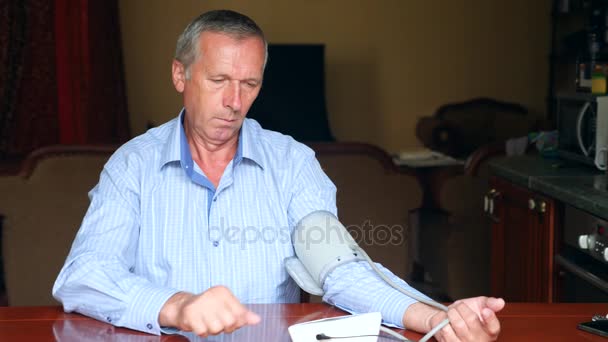 Elderly man measuring blood pressure. An old man sitting in his house at the table. 4k, slow motion. copy space — Stock Video