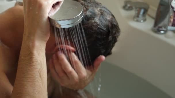 A fiatalember a hajmosás alatt tusoló. Az ember mossa a haját otthon. 4k, lassú mozgás — Stock videók
