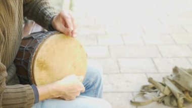 Bir sokak müzisyen bir Afrika davul çalıyor. Bongo davulunun üstündeki oynayan adam. yakın çekim. Bongo dokunarak el davul. 4k, ağır çekim çekim. Güneş parlamak.