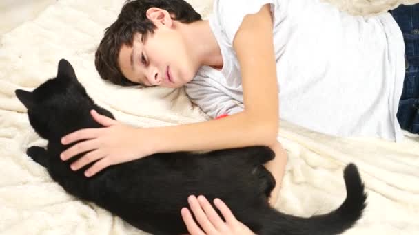 Мальчик обнимает и гладит своего питомца, чёрного кота. 4k, slow motion — стоковое видео