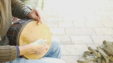 Bir sokak müzisyen bir Afrika davul çalıyor. Bongo davulunun üstündeki oynayan adam. yakın çekim. Bongo dokunarak el davul. 4k, ağır çekim çekim. Güneş parlamak.