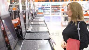 kadın bir müşteri bir elektronik mağazasında bir laptop seçer. 4k, ağır çekim