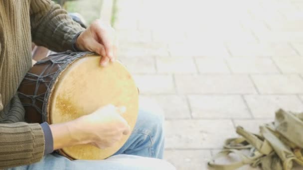 Een straat muzikant speelt op een Afrikaanse trommel. Man spelen op een Bongo trommel. Close-up. Hand te tikken op een Bongo trommel. 4k, slow-motion-video schieten. schittering van de zon. — Stockvideo