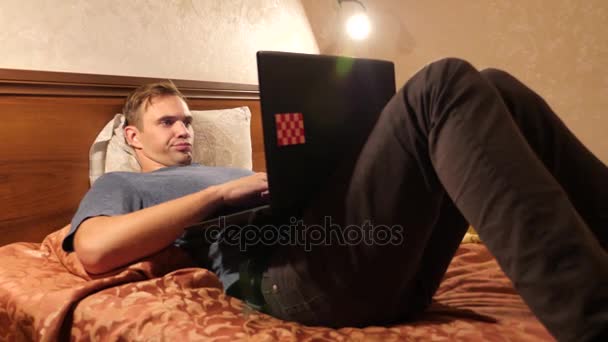 Álmos ember hordozható számítógépet az ágyban, késő este. 4k — Stock videók