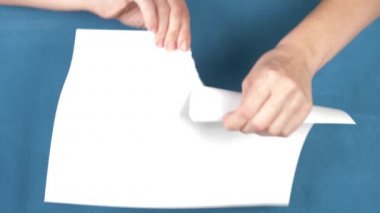 Kağıt levha, closeup turkuaz bir arka plan üzerinde yırtılma eller. 4k, ağır çekim
