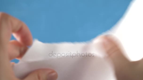 Hands tearing paper sheet, closeup on a turquoise background. 4k, slow motion — Stock Video