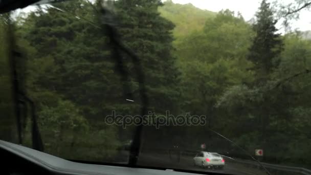 Zicht op de weg van de voorruit van de auto in de regen. Druppels water vallen op het glas, waardoor het moeilijk is om te bekijken. 4k, slow-motion — Stockvideo