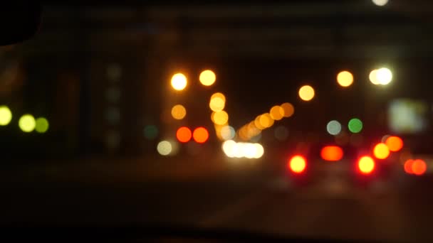 Jezdí v noci. rozmazaná auta ve městě. Osvětlené okno předního auta s rozmazaným městským provozem na ulicích města. 4k — Stock video