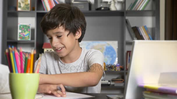 Концепция онлайн-обучения. ребенок записан в онлайн-школу. мальчик делает домашнее задание с ноутбуком. 4k, slow motion — стоковое видео