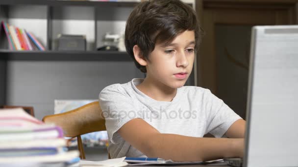 Koncept výuky online. dítě je zařazeno v online škole. chlapec, dělá domácí práce s přenosným počítačem. 4k, pomalý pohyb — Stock video