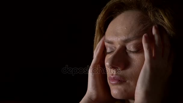 Close-up, sad woman with a headache on a dark background. 4k, slow motion — Stock Video