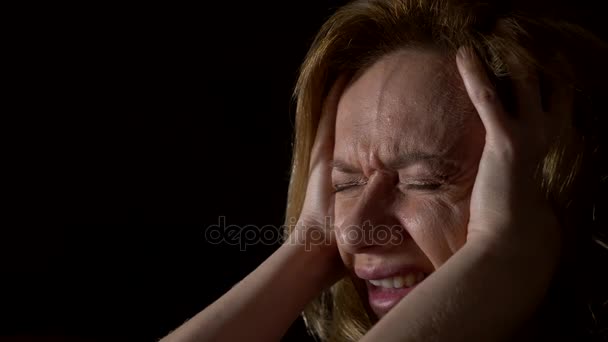 Close-up, trieste vrouw met een hoofdpijn op een donkere achtergrond. 4k, slow-motion — Stockvideo