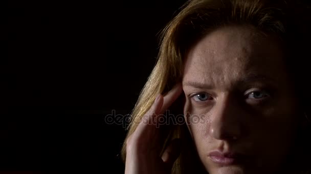 Close-up, mulher triste com uma dor de cabeça em um fundo escuro. 4k, câmera lenta — Vídeo de Stock