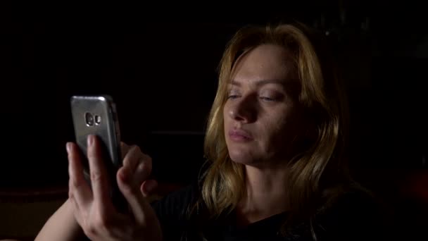 Женщина пользуется мобильным телефоном ночью. Закрывай, копируй пространство. 4k, slow motion — стоковое видео