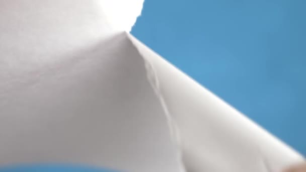 Mãos rasgando folha de papel, close-up em um fundo turquesa. 4k, câmera lenta — Vídeo de Stock