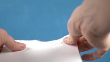 Kağıt levha, closeup turkuaz bir arka plan üzerinde yırtılma eller. 4k, ağır çekim