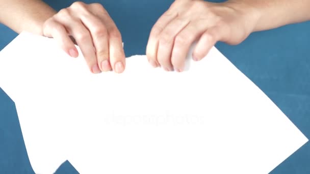 Mains déchirer feuille de papier, gros plan sur un fond turquoise. 4k, au ralenti — Video