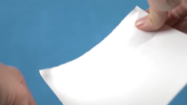 Руки розривають аркуш паперу, крупним планом на бірюзовому фоні. 4k, повільний рух — стокове відео