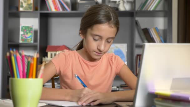 Концепция онлайн-обучения. ребенок записан в онлайн-школу. девушка делает домашнее задание с ноутбуком. 4k, slow motion — стоковое видео