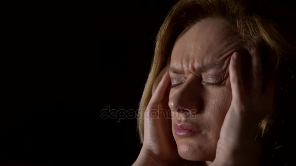 Close-up, mulher triste com uma dor de cabeça em um fundo escuro. 4k, câmera lenta — Vídeo de Stock
