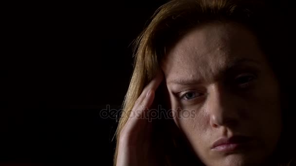 Close-up, sad woman with a headache on a dark background. 4k, slow motion — Stock Video