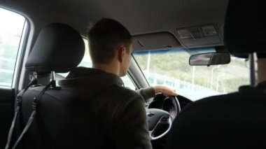 Yağmurda arabada ön cam yoldan görünümünü. Su damlaları görüntülemek zorlaştırır camına düşüyor. 4k, ağır çekim. adam direksiyon tutan.