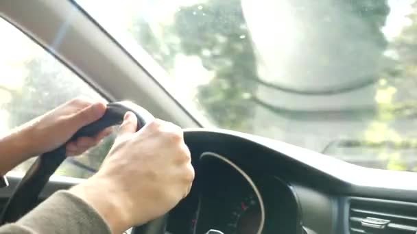 Vista de la carretera desde el parabrisas del coche bajo la lluvia. Gotas de agua caen sobre el vaso, por lo que es difícil de ver. 4k, cámara lenta. el hombre sostiene el volante . — Vídeos de Stock