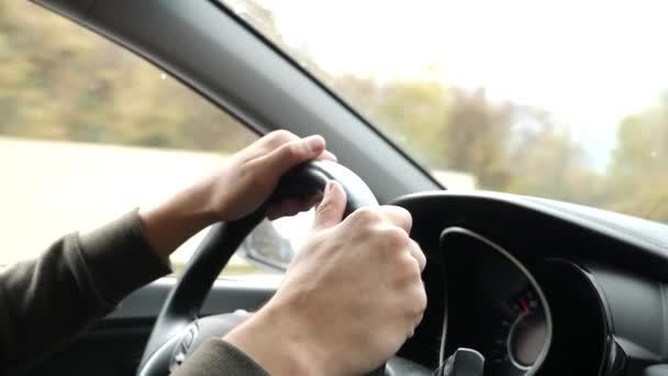 Pohled na silnici z čelního skla automobilu v dešti. Kapky vody padají na sklo, takže je obtížné zobrazit. 4k, zpomalené. muž drží volantu. — Stock video