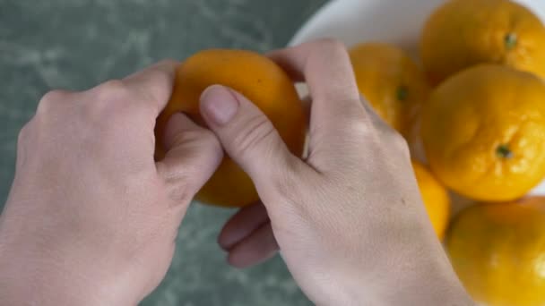 Womens händer skala skal av mandariner, mandarin skivor är staplade i en skål. 4k, Slowmotion — Stockvideo