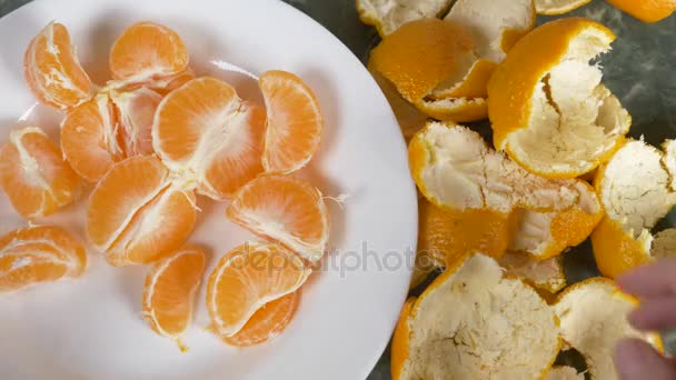 De handen van verschillende mensen nemen mandarijnen uit een plaat op tafel. 4k, slow-motion — Stockvideo