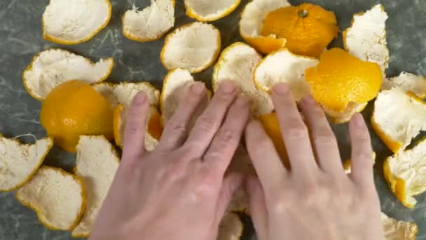 Las manos de las mujeres quitan la cáscara de mandarina de la mesa. 4k, grabación en cámara lenta, espacio para copiar — Vídeos de Stock